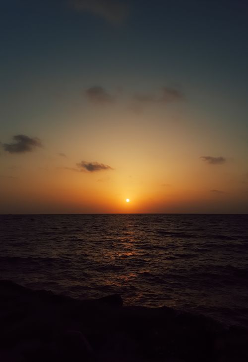 Free A serene sunset over the ocean with clear skies and calm waters. Perfect for nature enthusiasts. Stock Photo