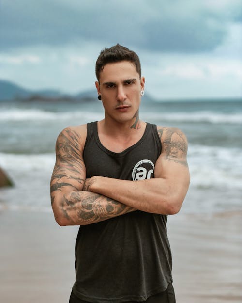 A man with tattoos standing on the beach