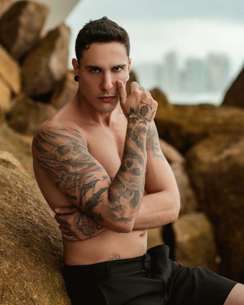 Topless Handsome Man with Tattoos Posing near Rock
