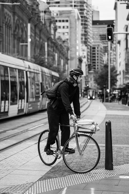 Free Black and white photo of a cyclist pausing on a busy city street in Sydney, Australia. Stock Photo