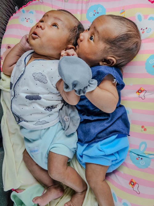 Free Two babies laying on top of each other in a crib Stock Photo