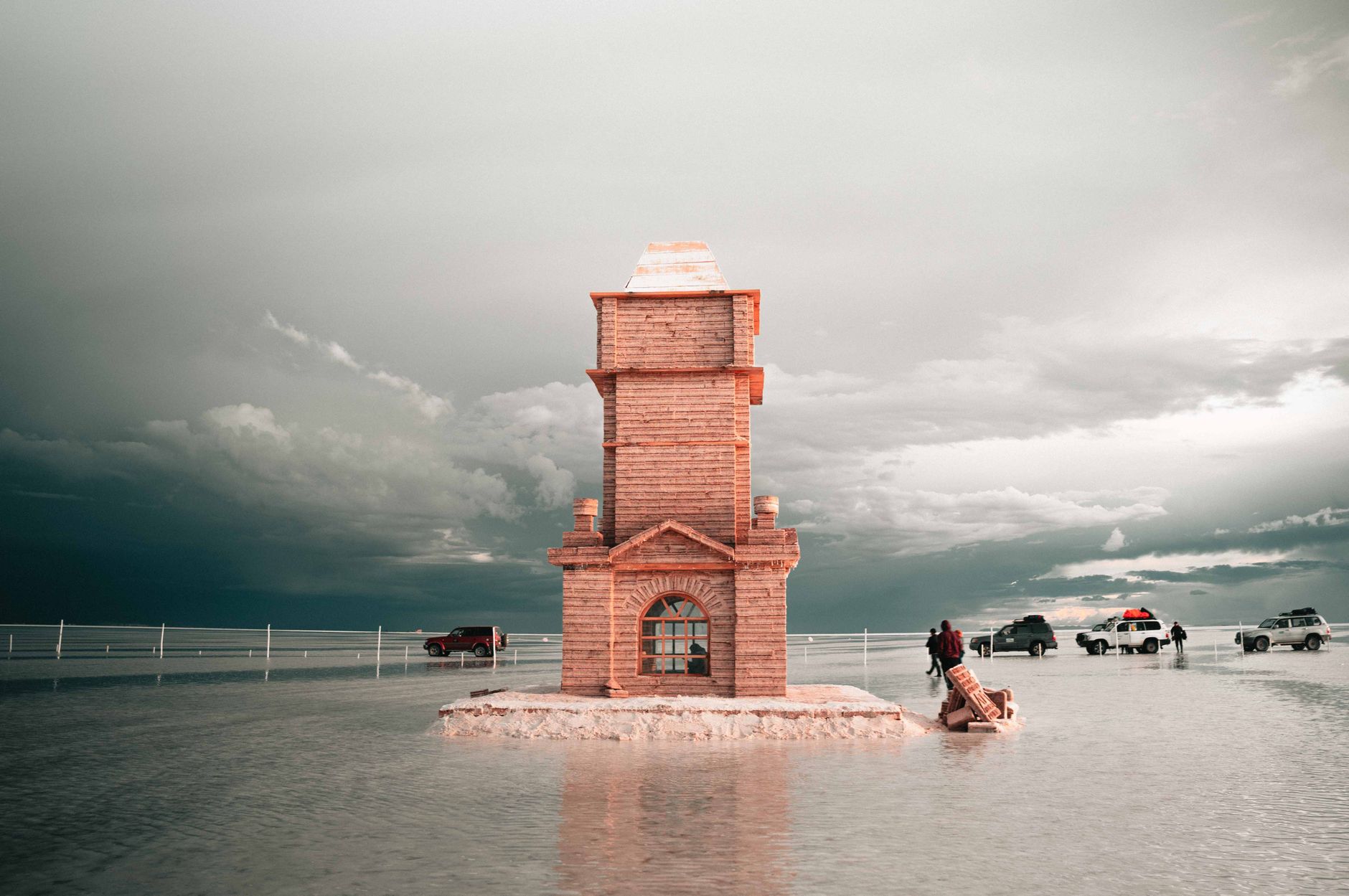 Photography of a striking tower in the vast Salar de Uyuni salt flat in Bolivia, with vehicles and a reflective surface.. Photo by Lyon Peru on Pexels