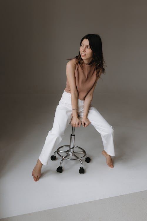 Free A woman sitting on a stool in a studio Stock Photo