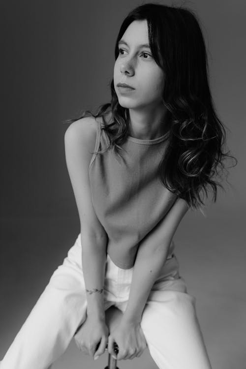 A woman in a white top and jeans posing for a black and white photo