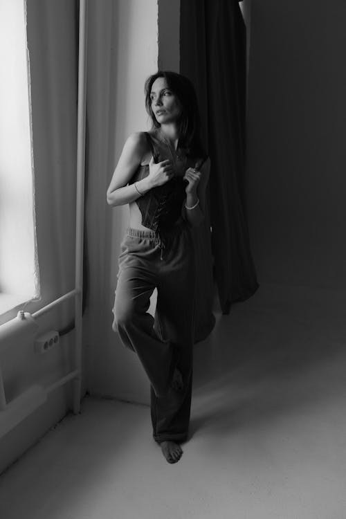 Free A woman in a black and white photo is standing in front of a window Stock Photo