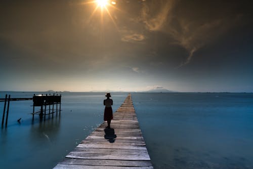 Silhouette Of Person Standing On Dock