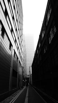 伦敦现代城市小巷的黑白景观充满戏剧性，摩天大楼笼罩在雾霭之中