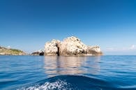 蔚蓝的天空下，一座岩石岛屿宁静地矗立，四周环绕着平静的海水