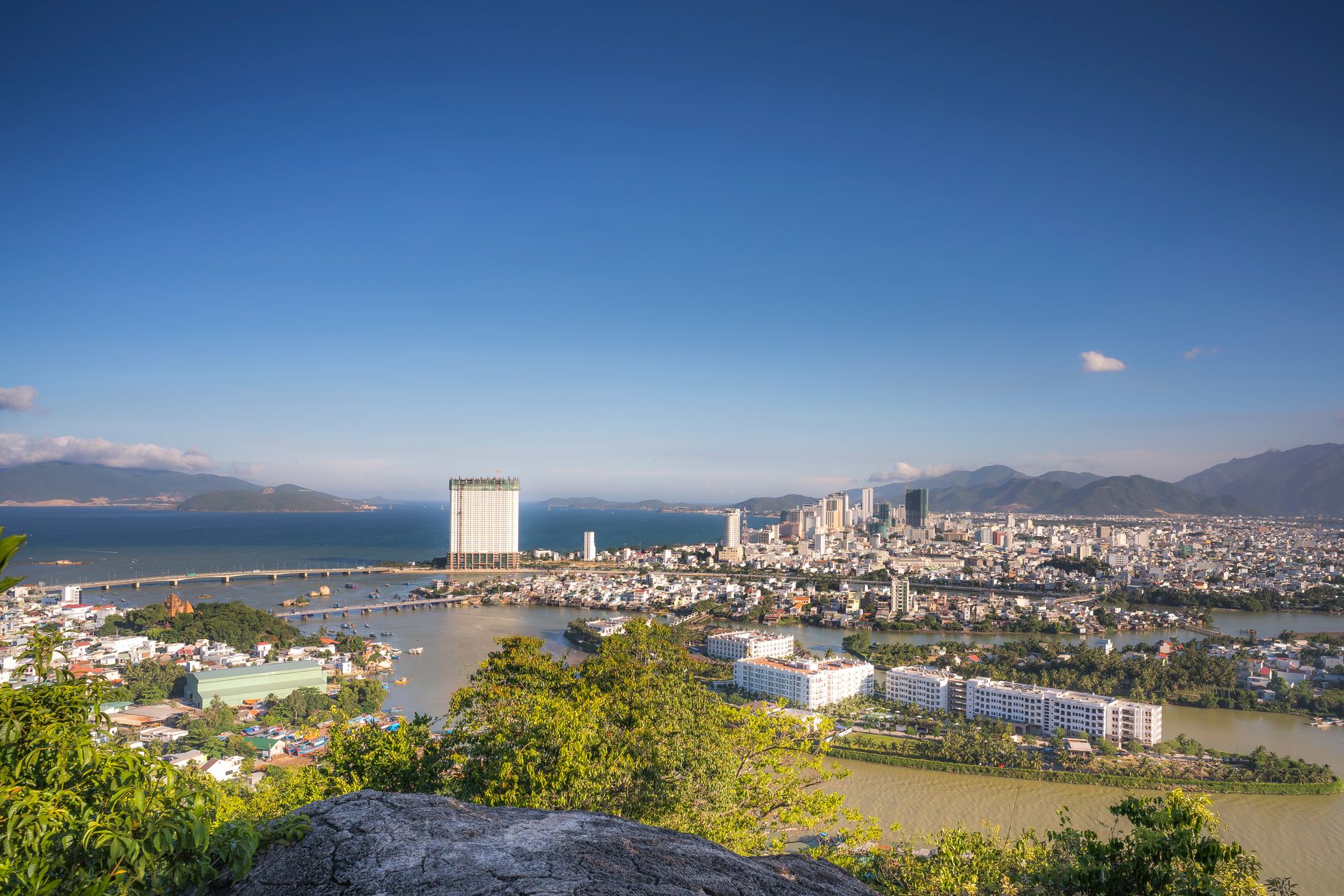 Stunning aerial view of a coastal city with ocean skyline and urban architecture under clear blue skies.