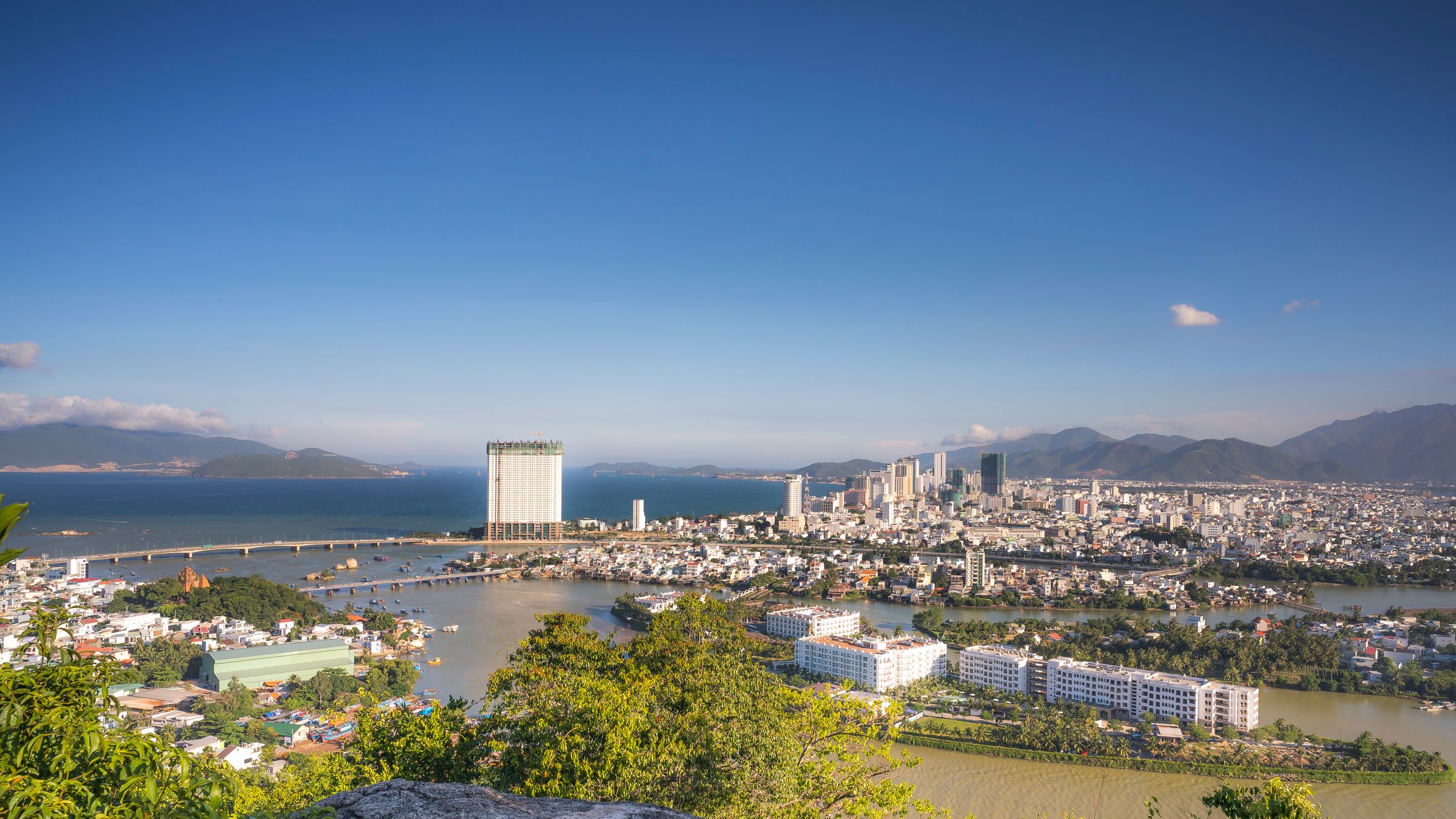 Stunning aerial view of a coastal city with ocean skyline and urban architecture under clear blue skies.