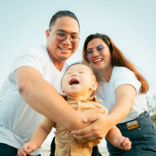 A man and woman holding a baby and smiling