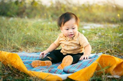 Free A baby sitting on a blanket in the grass Stock Photo