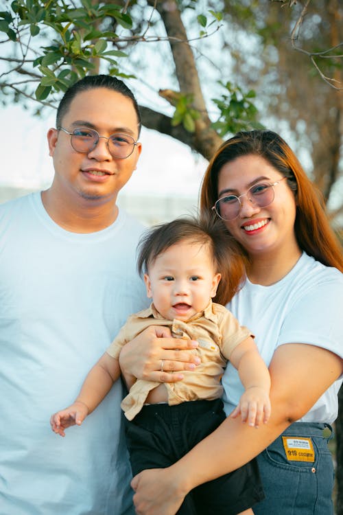 Free A man and woman holding a baby in front of a tree Stock Photo