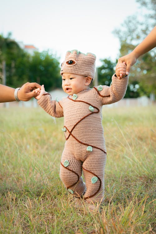 Free A baby in a brown and green costume walking Stock Photo