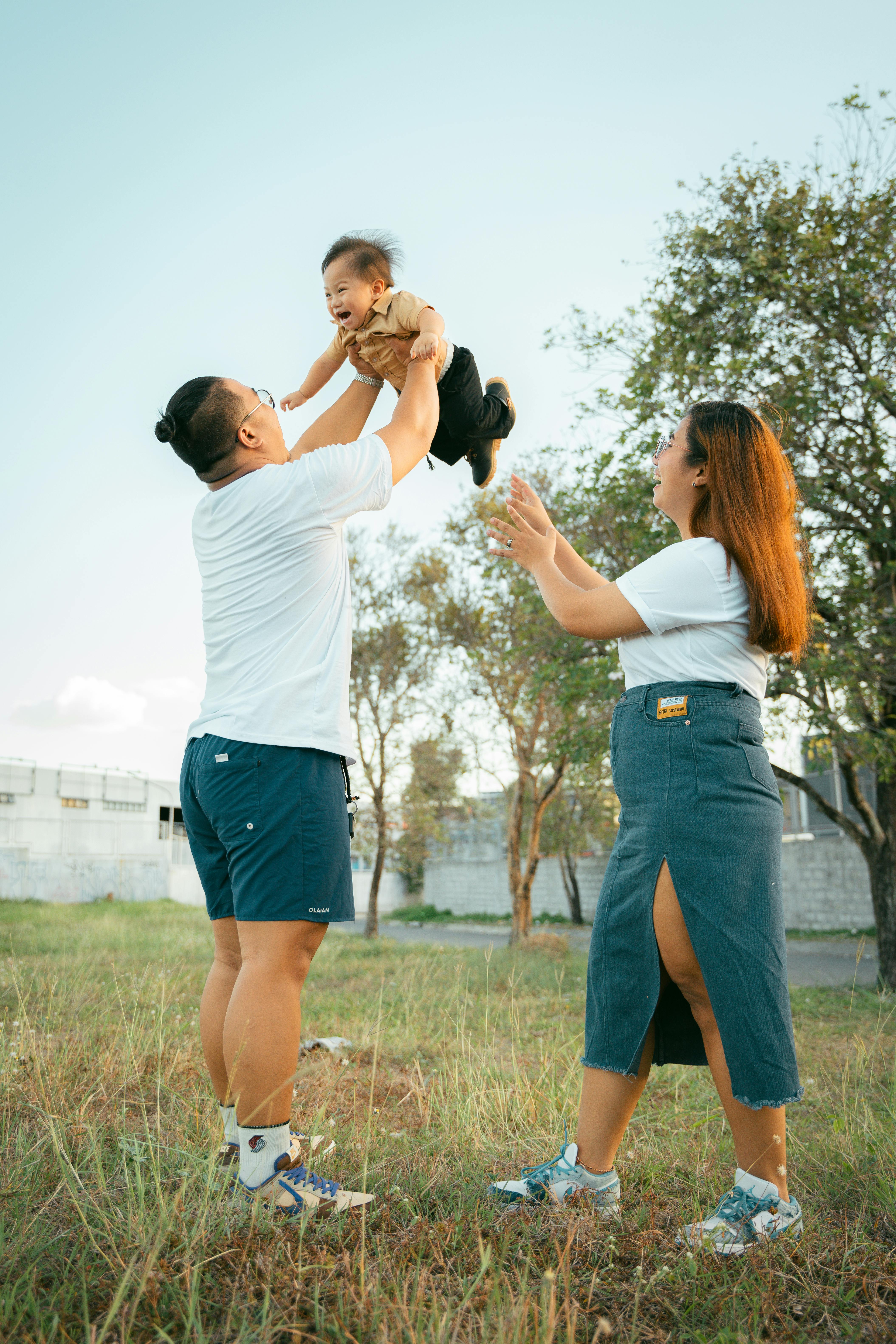 smiling mother and father lifting son at park