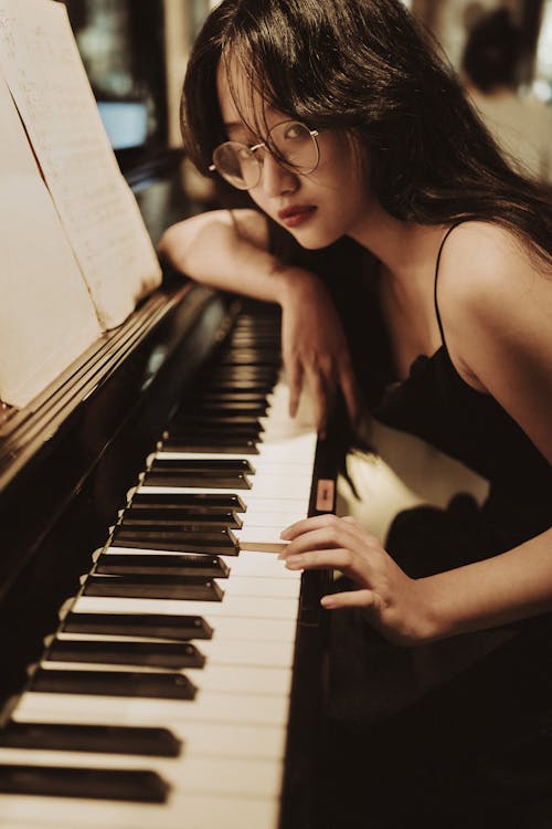A woman in glasses playing the piano