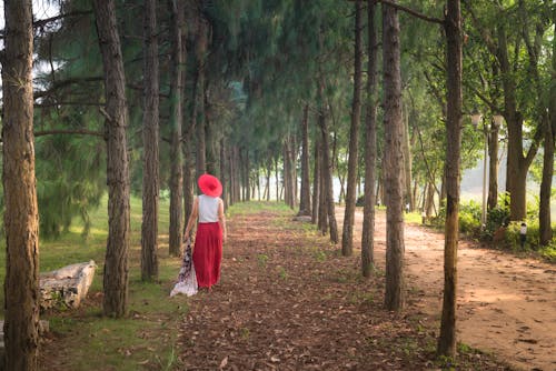 Mulher Usando Vestido Branco E Vermelho E Chapéu Vermelho Em Pé Ao Lado De Uma árvore Alta