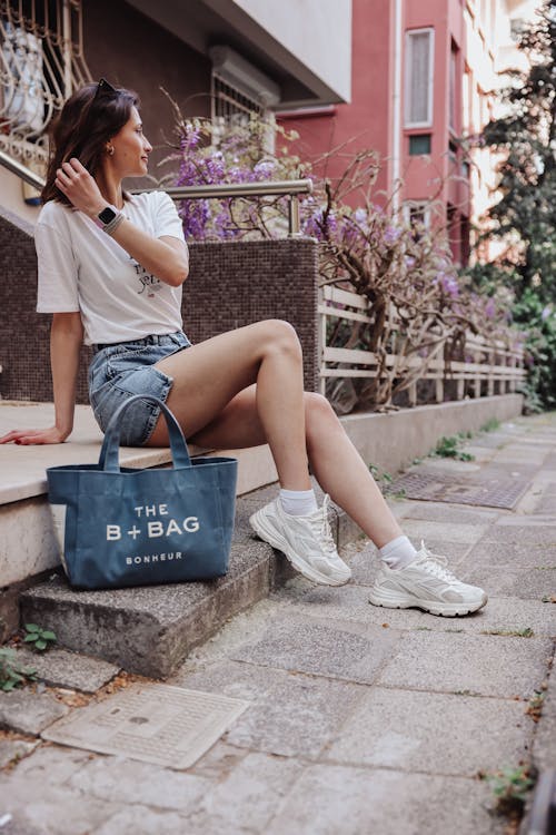 A woman sitting on steps with a tote bag