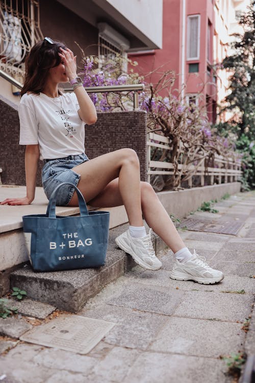 A woman sitting on steps with a tote bag