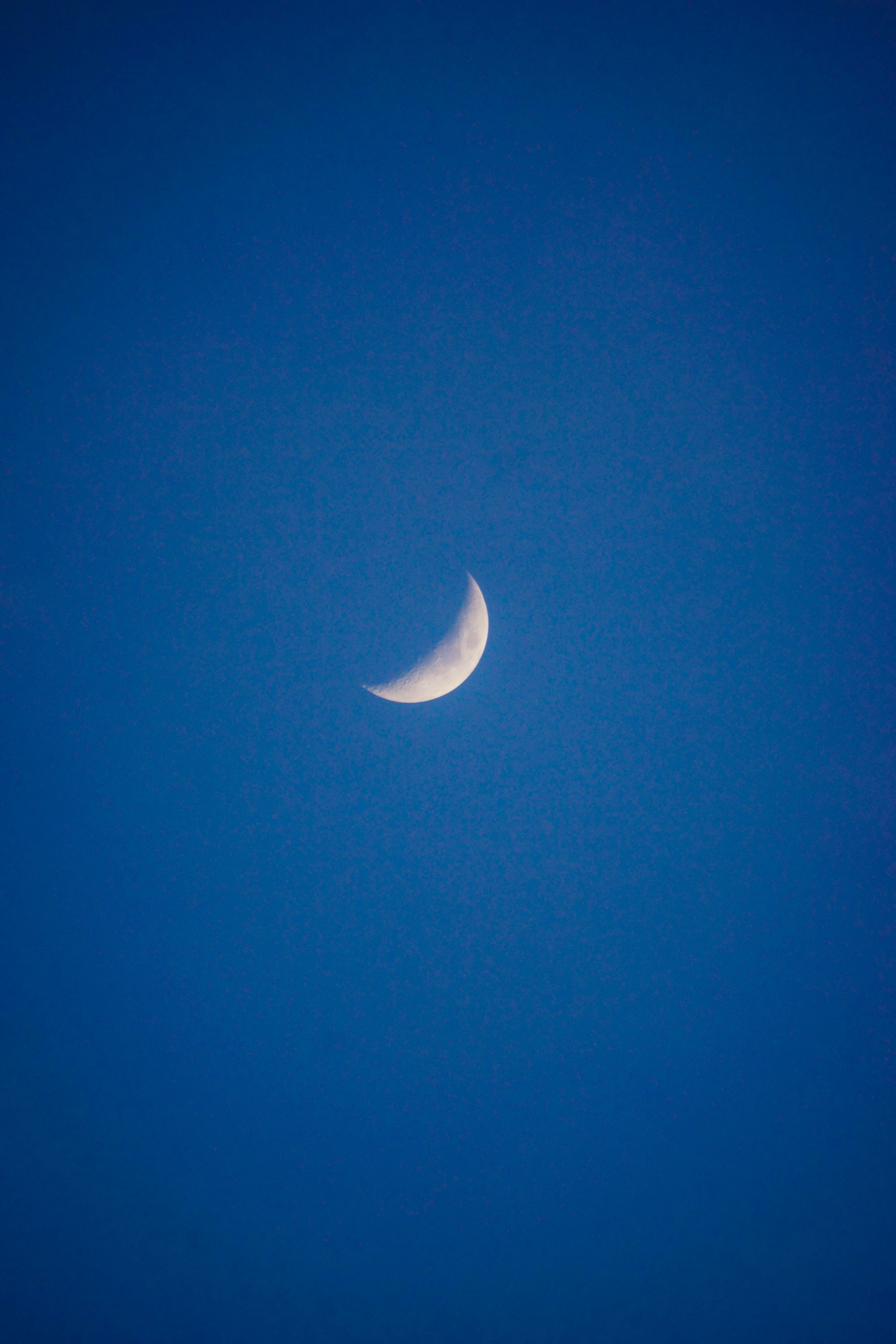 A serene crescent moon set against a vivid blue sky, perfect for night sky enthusiasts.