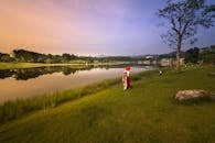 日落时分，一名戴红帽子的女子站在宁静的湖边，捕捉着这份宁静