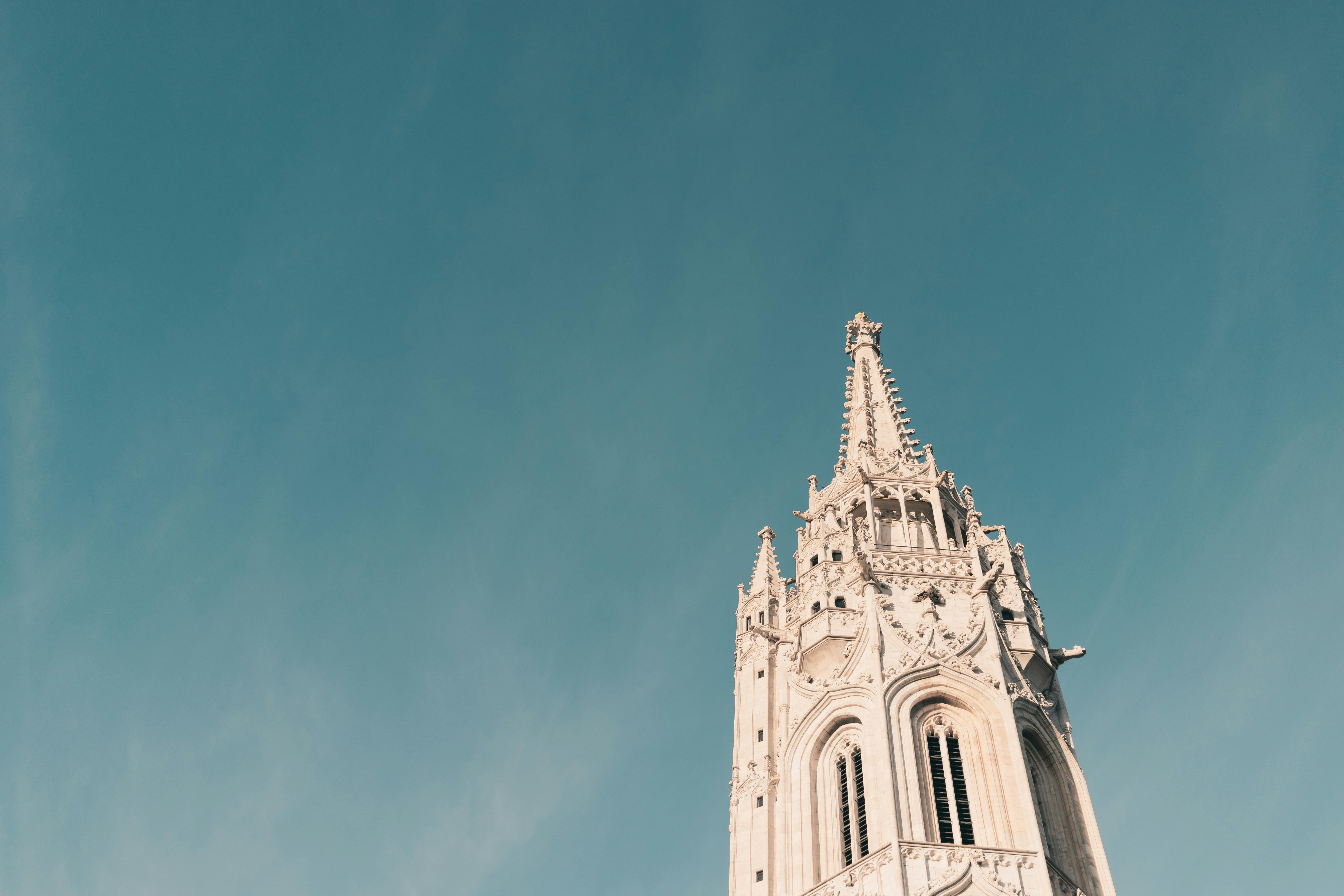 A low angle shot of the Matthias Church tower in Budapest against a clear blue sky.