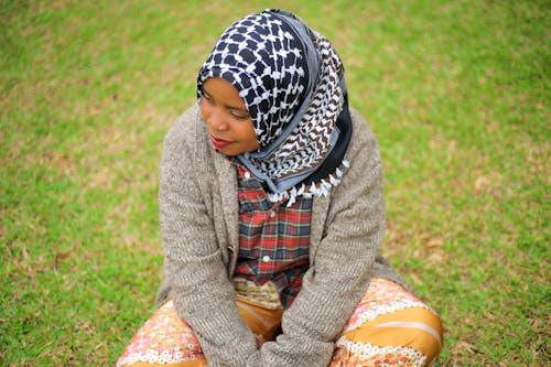 Free A Young Woman in a Headscarf Sitting on a Meadow Stock Photo