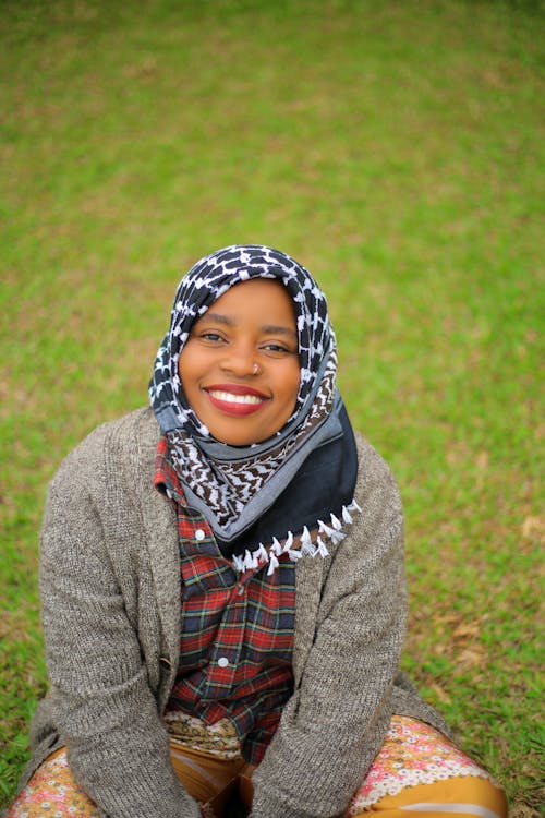 Free A smiling woman in a hijab sitting on the grass Stock Photo