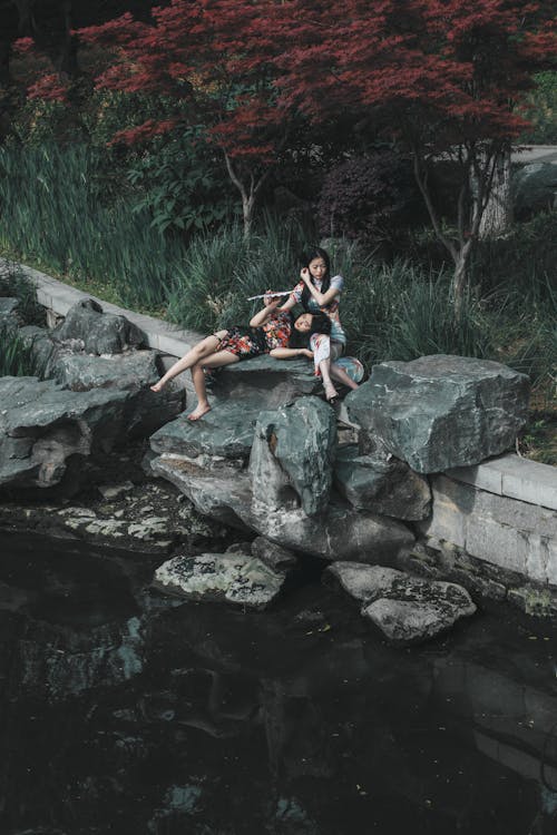 Free Two people sitting on rocks in a pond Stock Photo