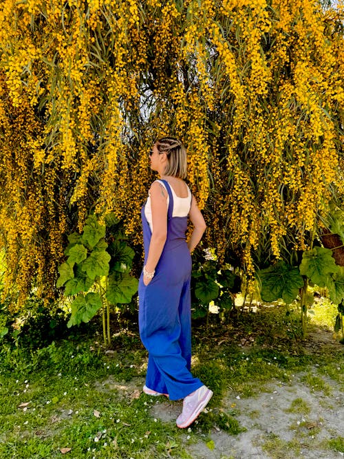 Free A Woman in a Blue Jumpsuit Standing next to a Tree in a Park  Stock Photo