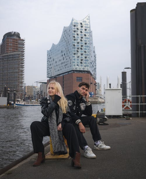 Free Two people sitting on a bench near a building Stock Photo