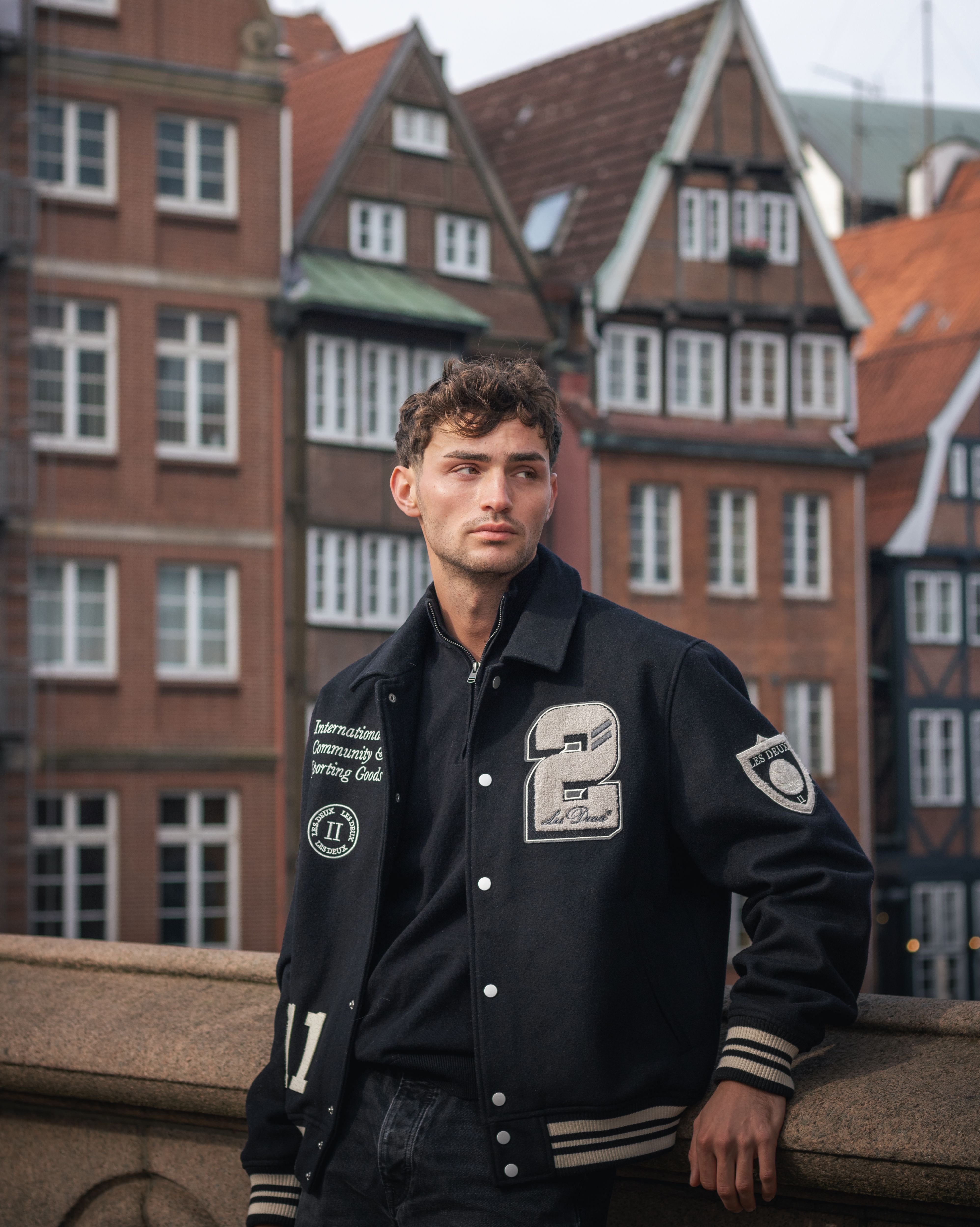 Man in a black jacket and casual trousers on a city street