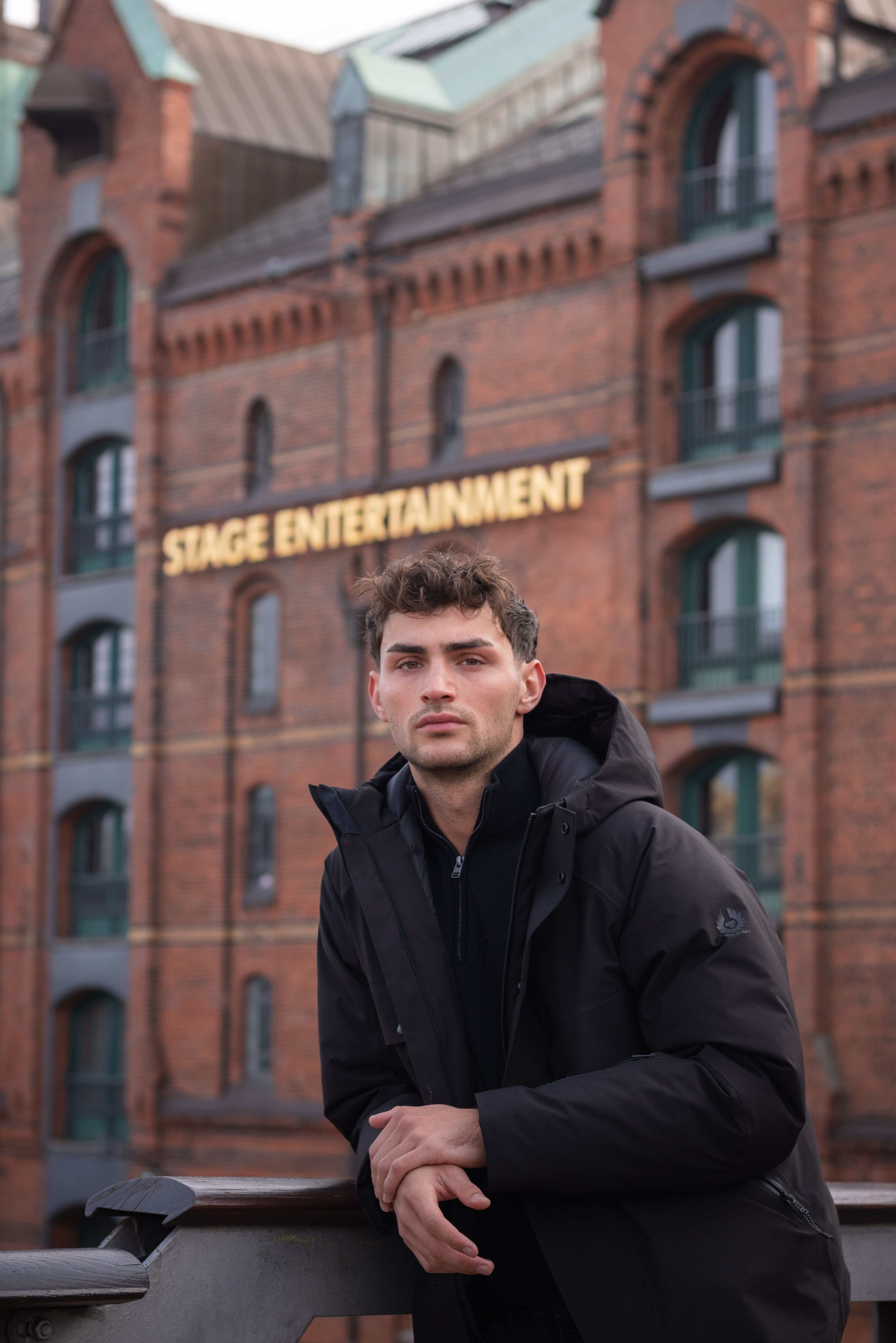 Young man posing in front of iconic brick building in Speicherstadt, Hamburg.