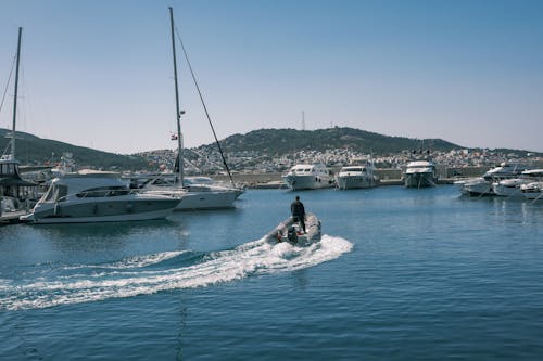 A man on a speedboat in the water near a marina