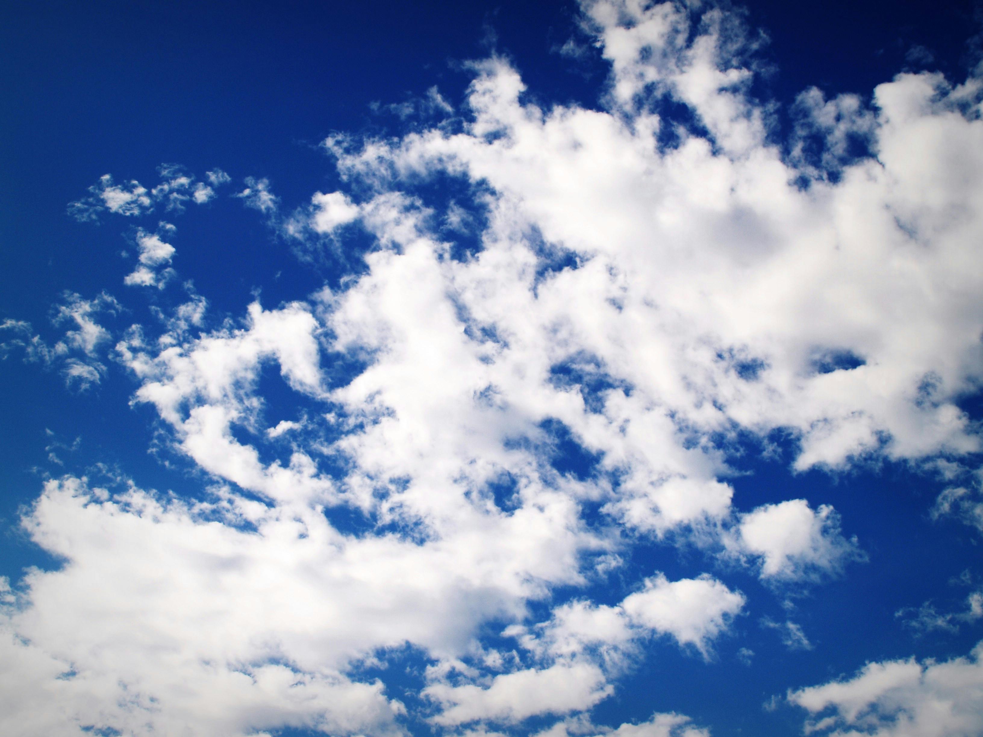 Clear blue sky with scattered white fluffy clouds creating a serene cloudscape.