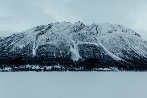 A snowy mountain with a snow covered lake