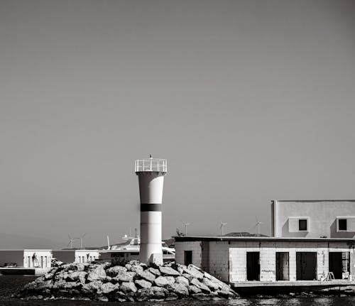 Free A black and white photo of a lighthouse on a pier Stock Photo