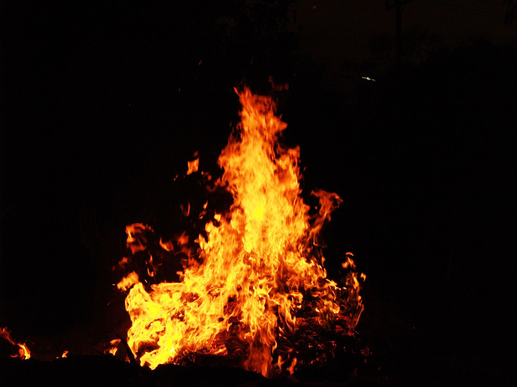 Dramatic image of a brightly burning bonfire against a dark night backdrop.