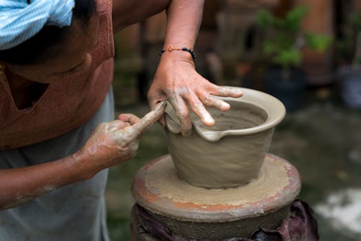 Close-up of a skilled artisan crafting a clay pot by hand on a spinning wheel outdoors.