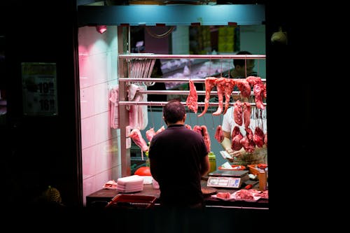 Mann, Der Vor Stall Mit Gehängtem Fleisch Steht