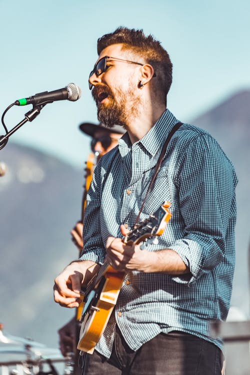 Shallow Focus Photo of Man Playing Brown Electric Guitar
