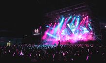 Unrecognizable musicians performing on concert hall stage illuminated by colorful spotlights in front of public in evening