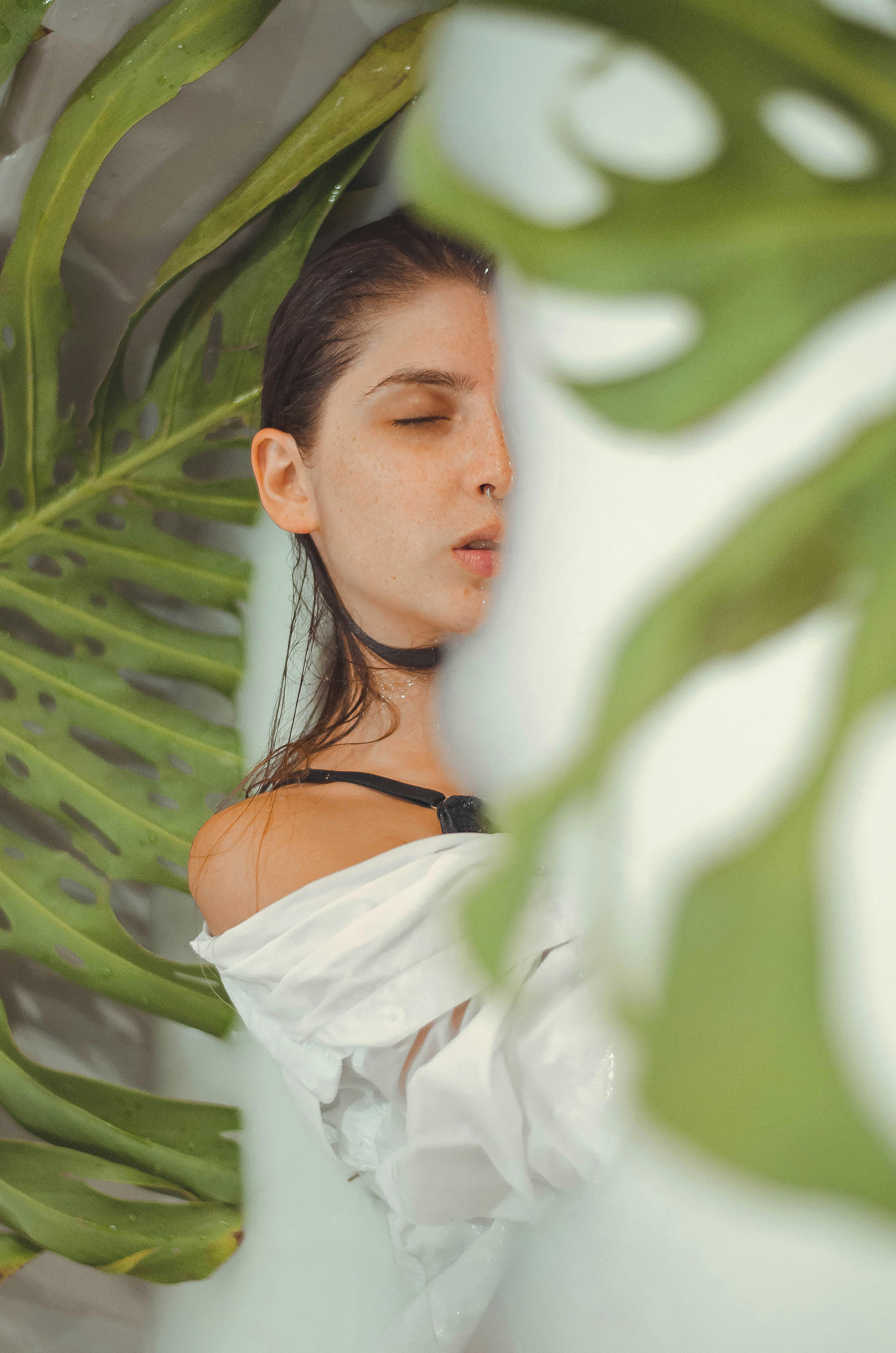 郁郁葱葱的绿叶包围着白衣女子，散发着优雅与放松的气息