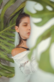 郁郁葱葱的绿叶包围着白衣女子，散发着优雅与放松的气息