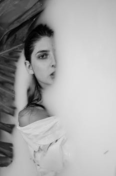 Striking monochrome portrait of a woman partially obscured by mist and leaves.