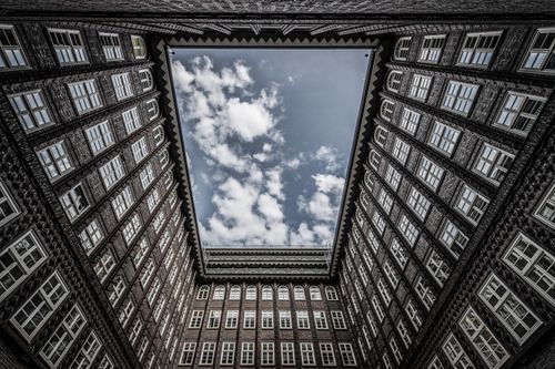 Free Dramatic upward view of Chilehaus courtyard in Hamburg, capturing the sky framed by brick architecture. Stock Photo