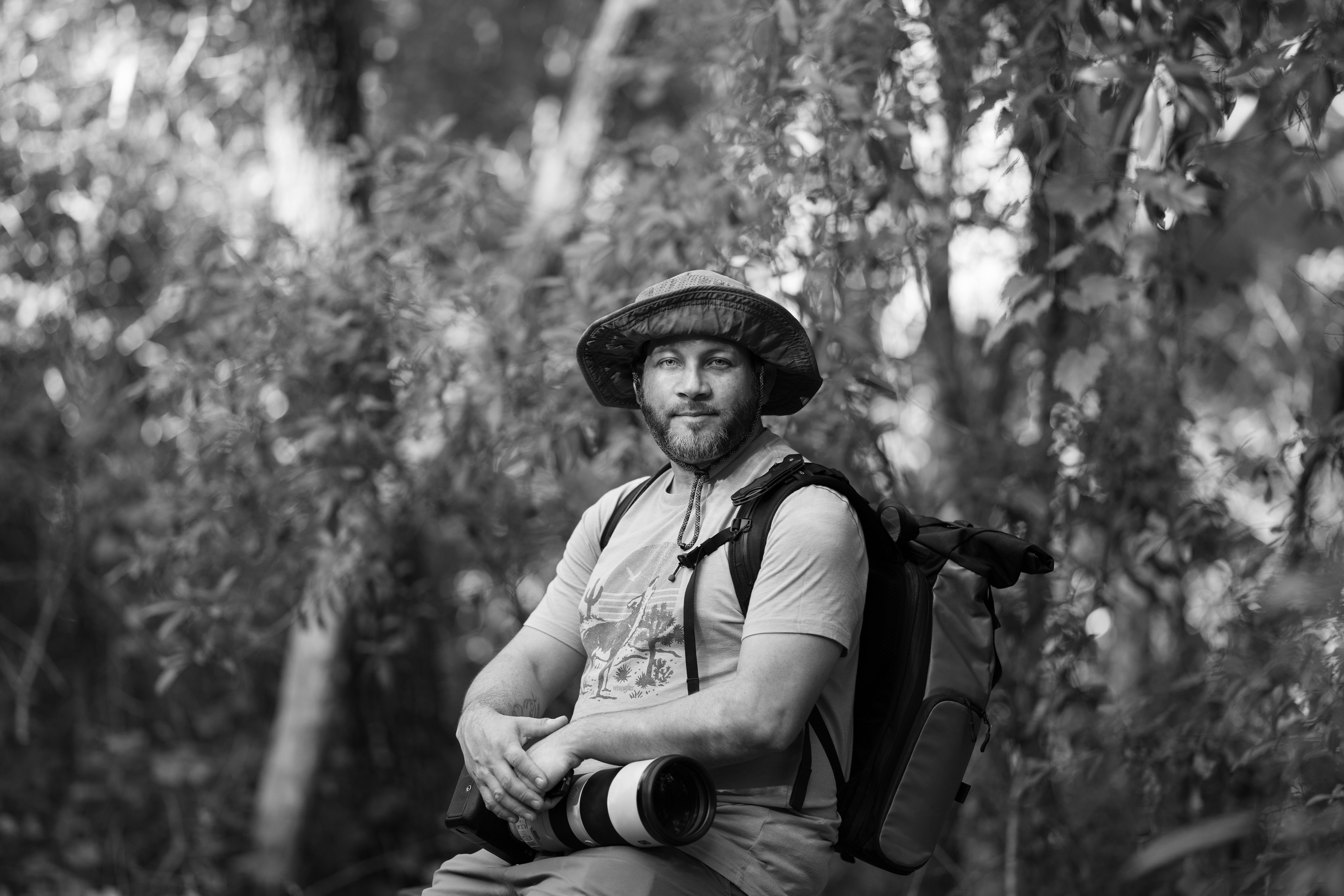 Black and white portrait of a photographer with camera in Shady Hills forest.