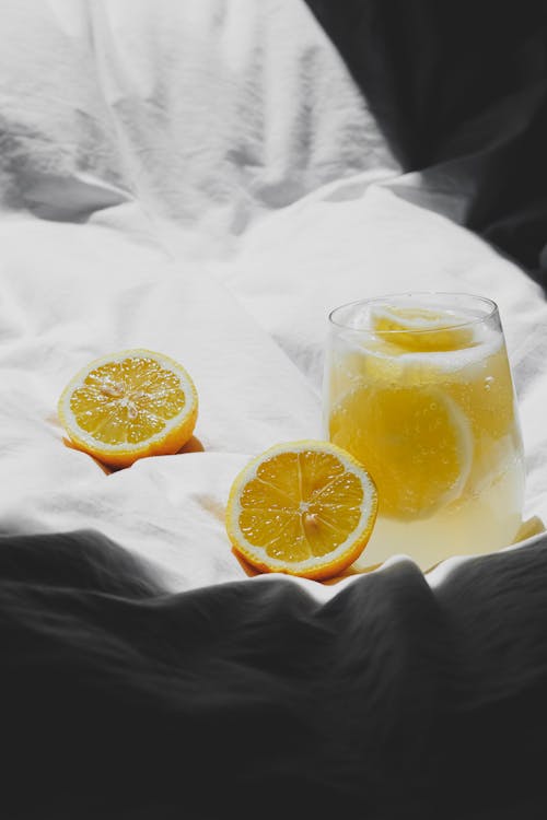 A glass of lemonade on a bed with a lemon slice