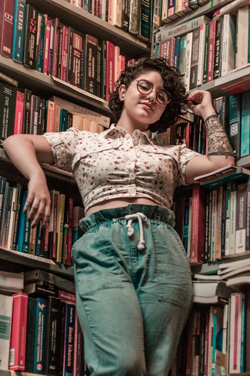 Free Woman Leaning on Bookshelf Stock Photo
