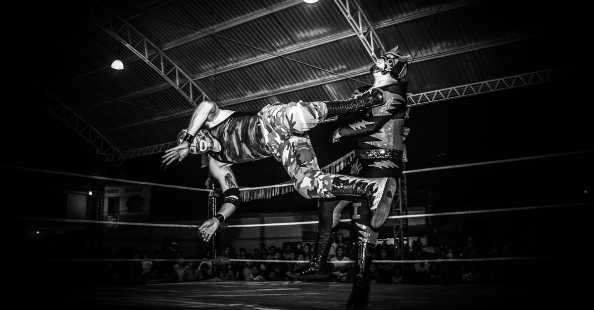 Intense Lucha Libre wrestling match showcasing strength and agility under dramatic lighting.